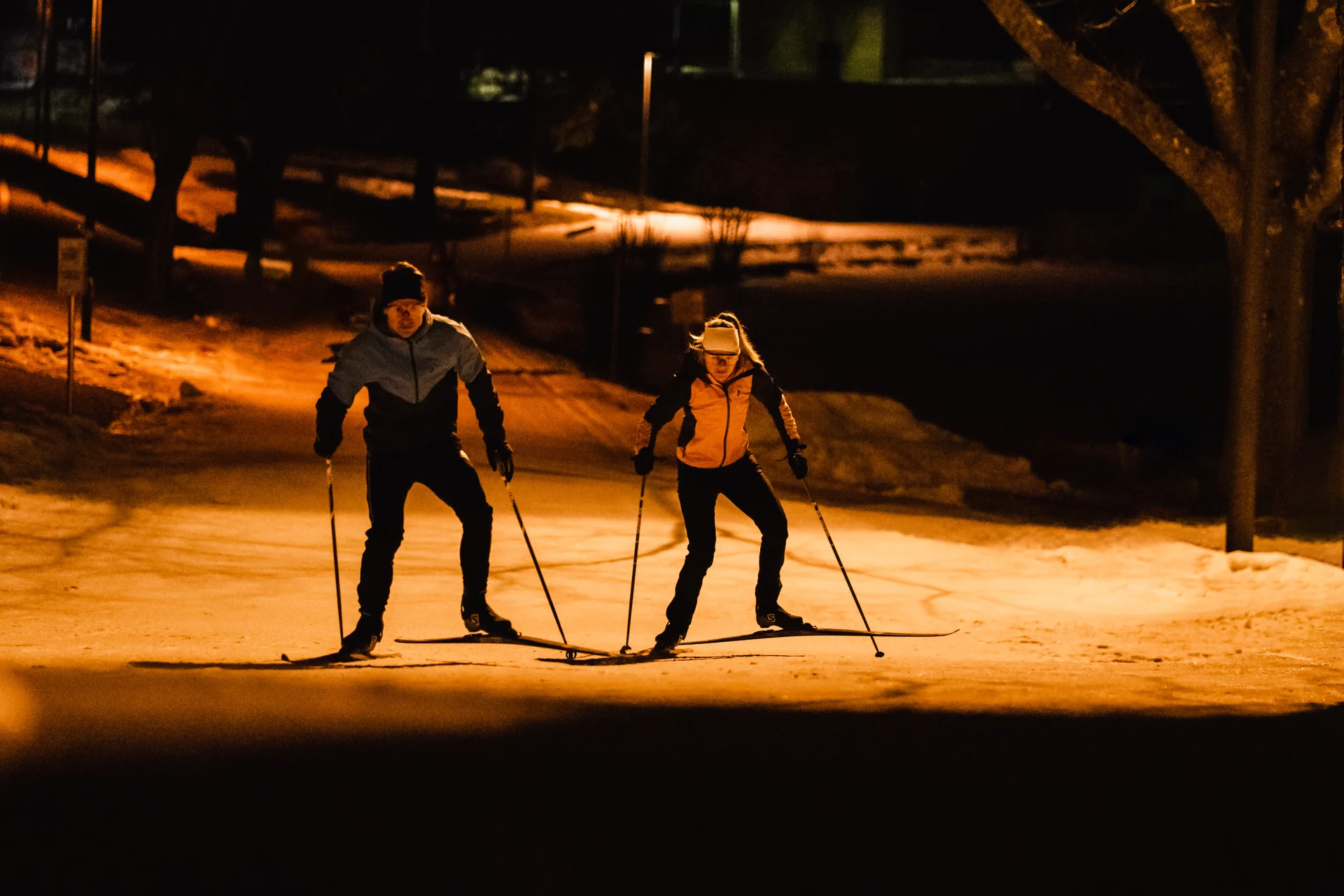 Langläufer-Paar auf beleuchteter Nachtloipe im Winter