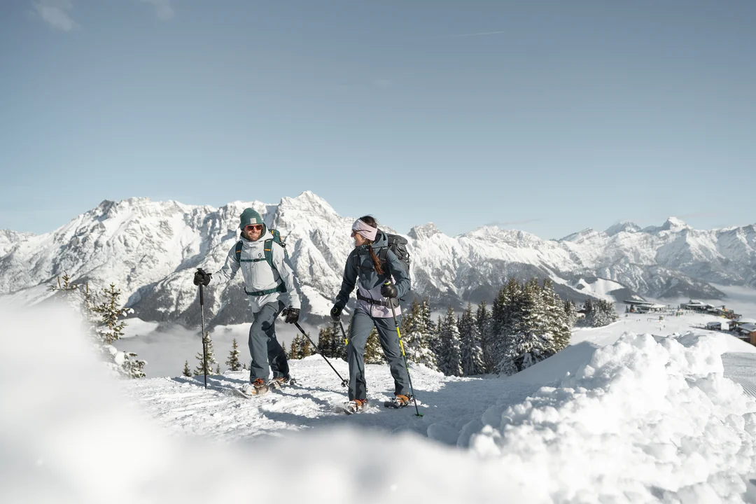 Schneeschuhwanderer-Paar am Gipfel mit Steinberge-Panorama