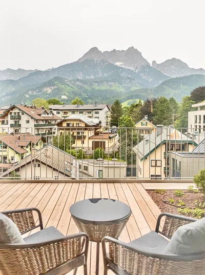 Dachterrasse mit Rattansesseln und Blick auf Saalfelden und die Steinberge