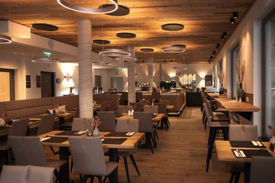 Restaurant-Innenraum mit Holzdecke, Ringlicht-Pendelleuchten und gedeckten Tischen