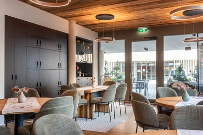 Lounge-Bereich mit grünen Sesseln, dunklem Schrank und Terrassenblick