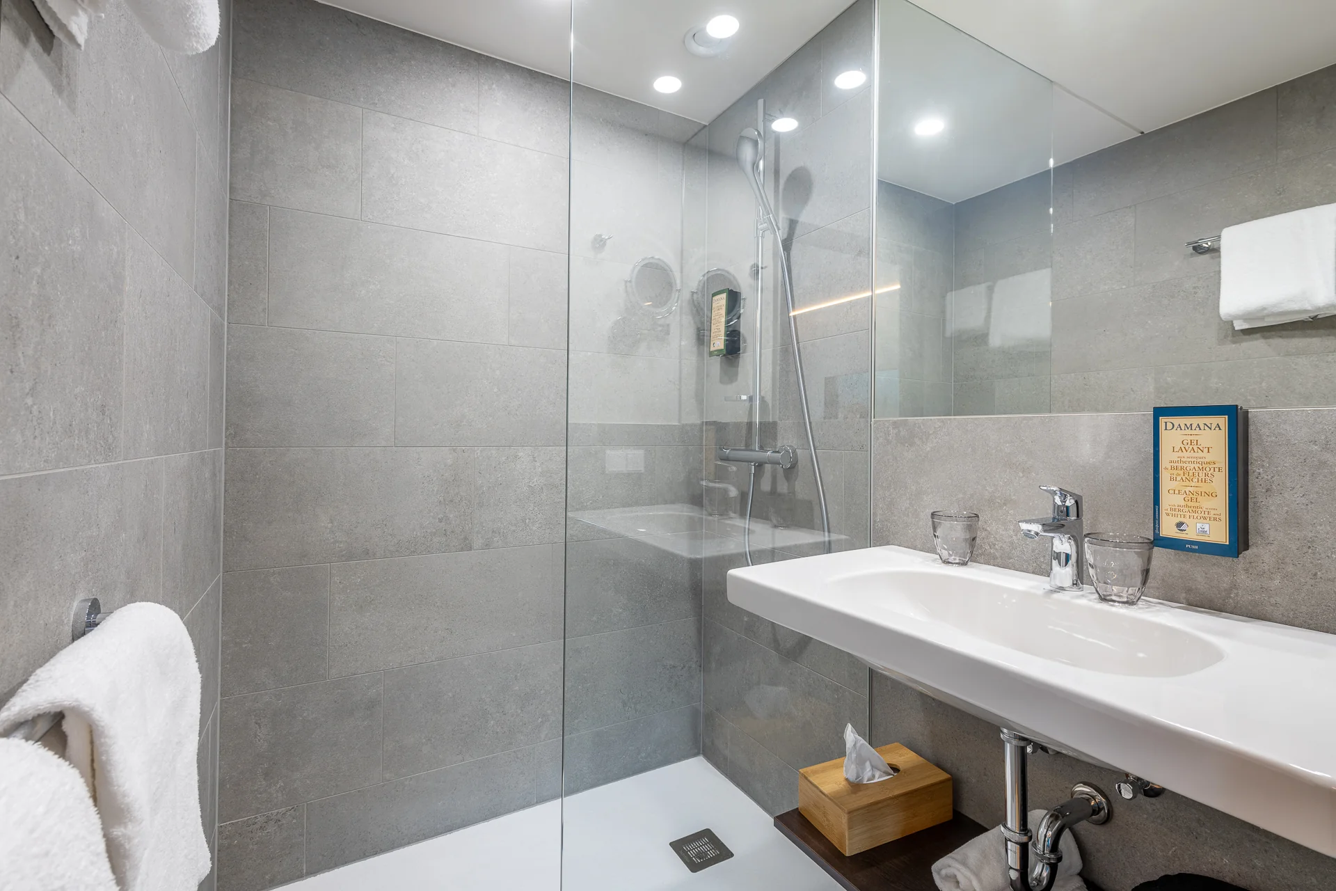 Modernes Badezimmer mit grauen Natursteinfliesen, Regendusche und Hotelzertifikat