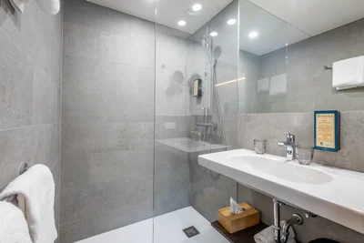 Modernes Badezimmer mit grauen Natursteinfliesen, Regendusche und Hotelzertifikat