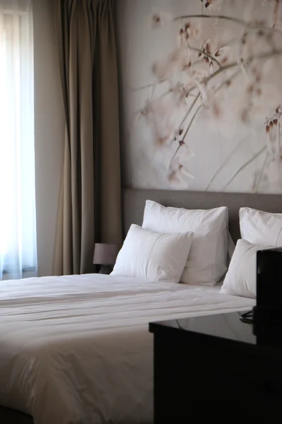 Gemütliches Doppelzimmer Classic mit zartem Blütenmotiv-Wandbild, weißer Bettwäsche und beigen Vorhängen