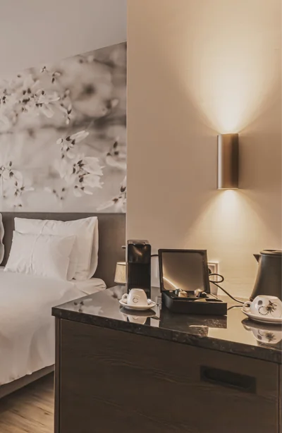 Zimmeransicht mit Blütentapete, Doppelbett und Minibar-Bereich mit Nespresso-Maschine und Wasserkocher