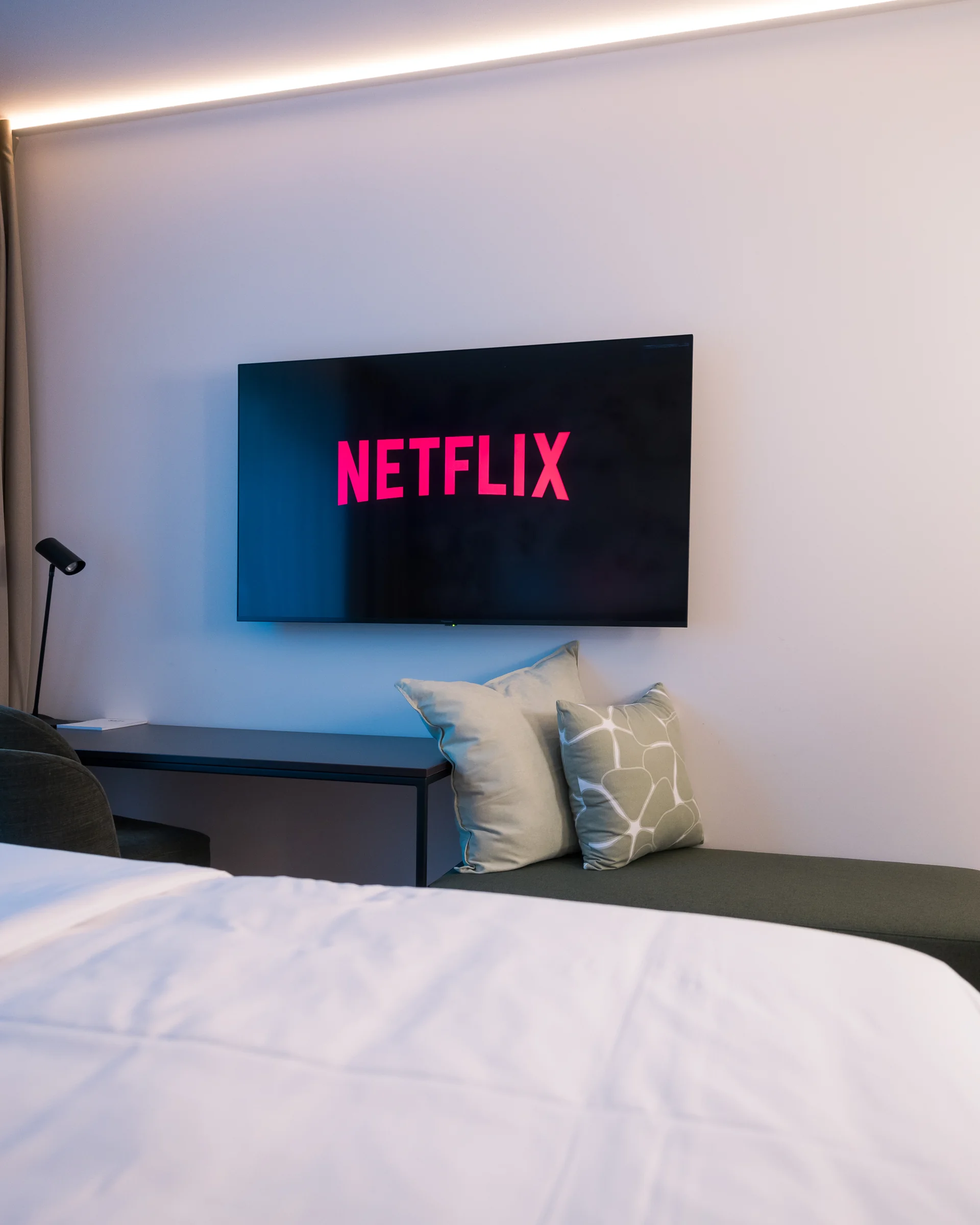 Smart-TV mit Netflix-Streaming über grüner Sitzbank mit modernen Dekokissen
