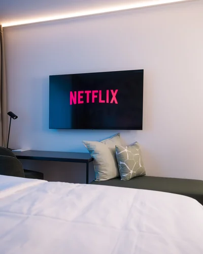 Smart-TV mit Netflix-Streaming über grüner Sitzbank mit modernen Dekokissen