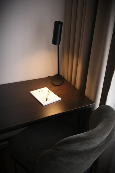 Stimmungsvoller Schreibtisch mit Das Saal Notizblock und eleganter schwarzer Tischlampe