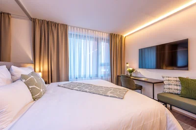 Elternschlafzimmer der Family Suite mit Doppelbett, Schreibtisch und wandmontiertem TV