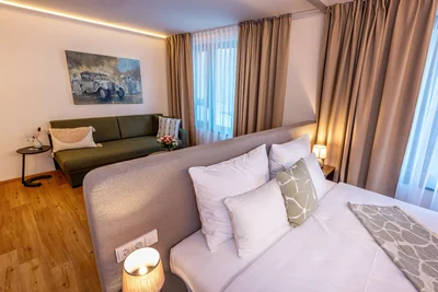 Schlafzimmer der Family Suite mit Oldtimer-Gemälde und grünem Sofa in warmer Atmosphäre