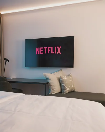 Smart-TV mit Netflix auf Wandhalterung, grüne Sitzbank mit Dekokissen und LED-Ambiente
