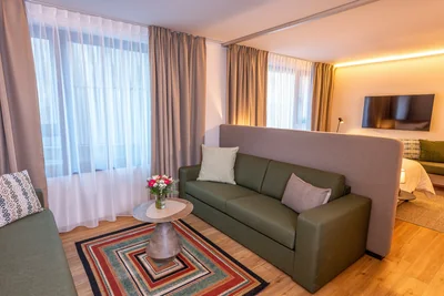 Family Suite Wohnbereich mit grünem Sofa und Blick zum eleganten Schlafbereich
