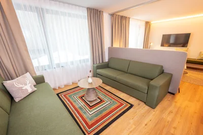 Gemütlicher Wohnbereich der Family Suite mit zwei grünen Sofas und geometrischem Streifenteppich