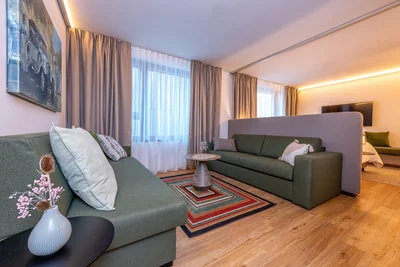 Gemütliche Wohnecke der Family Suite mit zwei grünen Sofas und buntem Streifenteppich