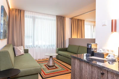 Wohnbereich der Family Suite mit zwei grünen Sofas, buntem Teppich und Nespresso-Kaffeemaschine