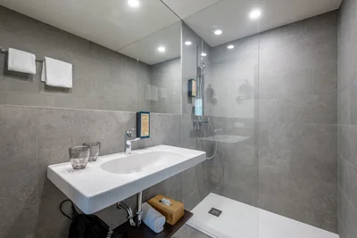 Elegantes Badezimmer mit grauen Natursteinfliesen, Regendusche und schwebendem Waschtisch