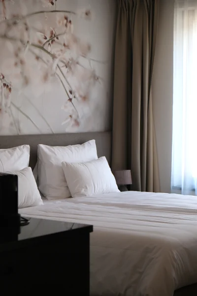 Gemütlicher Schlafbereich der Junior Suite mit zartem Blütenwandbild und weißer Bettwäsche