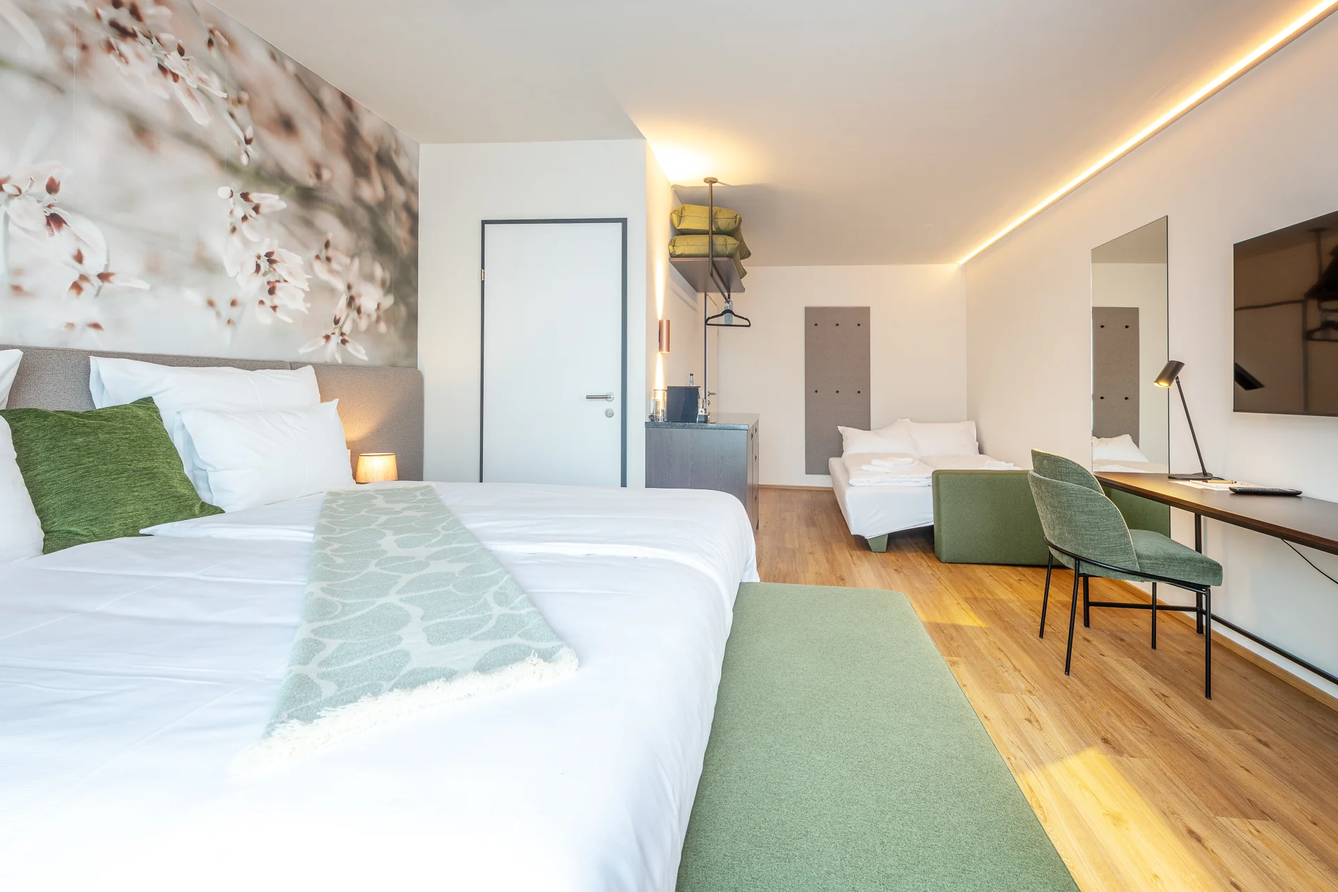 Junior Suite mit grünen Akzenten, gemusterter Tagesdecke und Blick auf den Tagesbett-Bereich