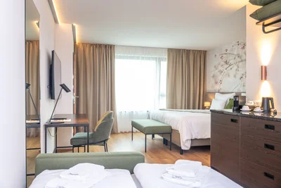 Panoramaansicht der Junior Suite mit Bett, grüner Sitzbank und Tagesbett