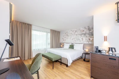 Blick vom Schreibtisch auf das Bett mit Blütentapete und kupferfarbenen Wandleuchten