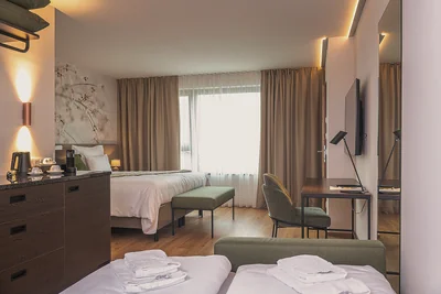 Geräumige Junior Suite mit Blütentapete, grüner Sitzbank und Tagesbett mit bereitgelegten Handtüchern