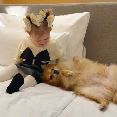 Kleines Maedchen mit Hund auf komfortablem Hotelbett