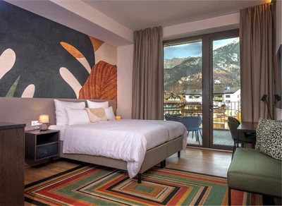 Zimmer mit tropischem Blätter-Wandmotiv und buntem Streifenteppich