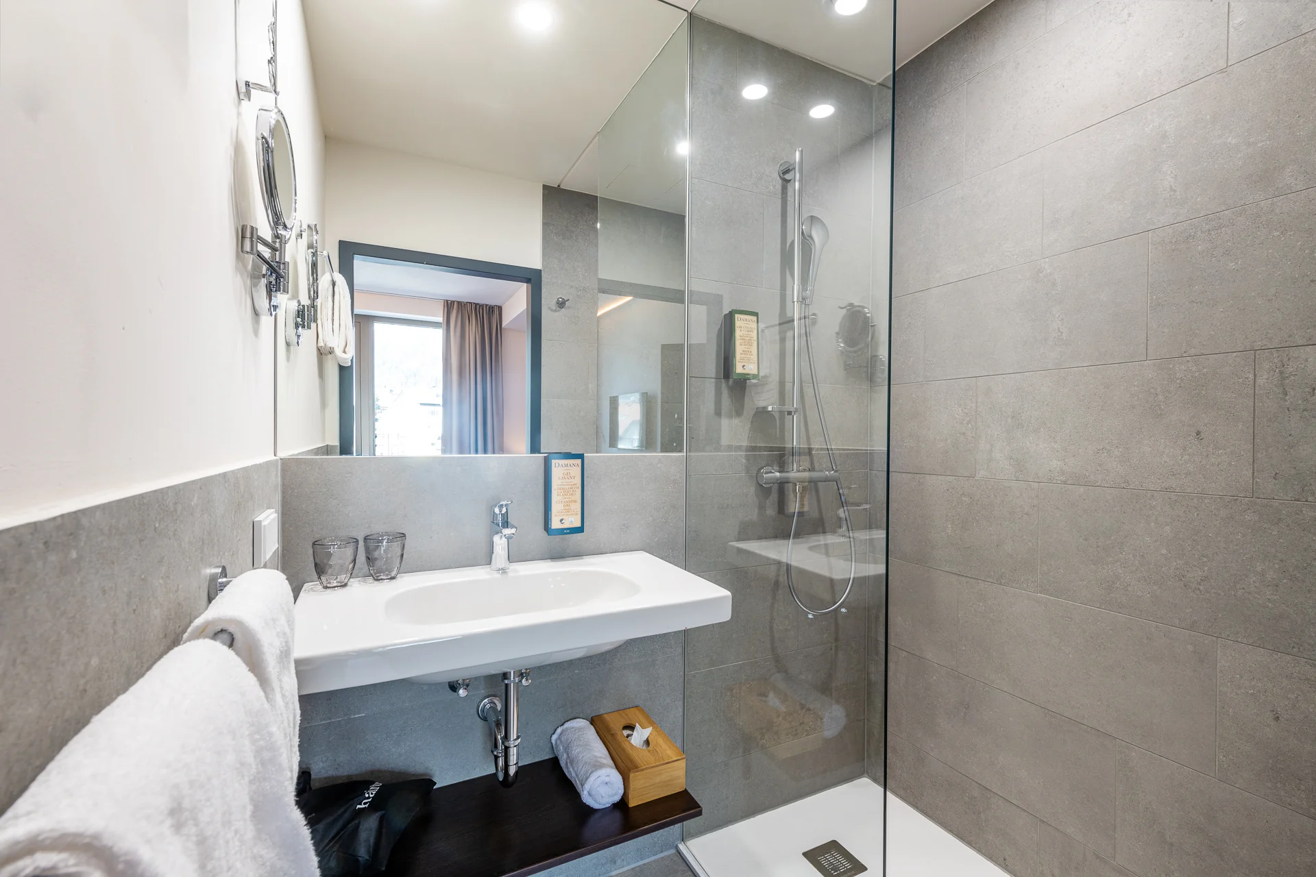 Modernes Badezimmer mit grauen Fliesen, Glasdusche und Waschtisch