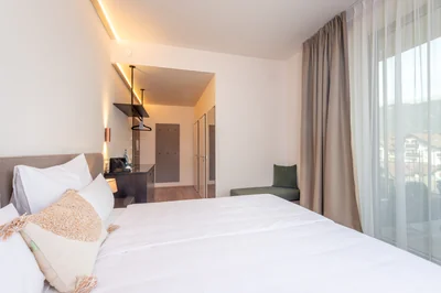 Helles Schlafzimmer mit Quasten-Kissen und Blick zum Eingangsbereich