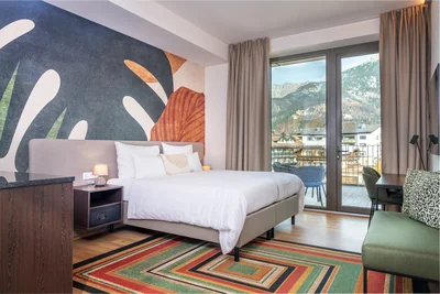 Schlafzimmer mit Monstera-Tapete, Streifenteppich und Bergblick