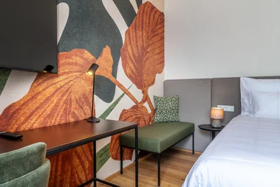 Detail mit Monstera-Tapete, grüner Sitzbank und Schreibtisch