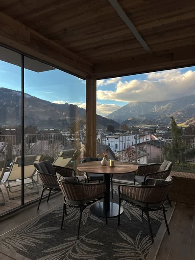 Überdachte Terrasse mit Rattansesseln und Steinberge-Panorama