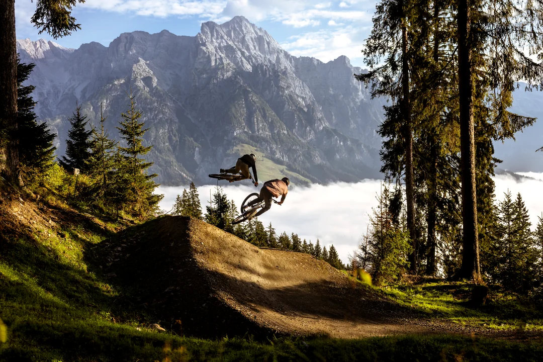 Two mountain bikers jumping in the bike park with Steinberge in the background