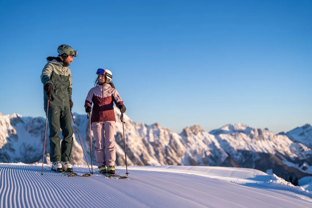 Skifahrer-Paar auf präparierter Piste bei Morgenlicht