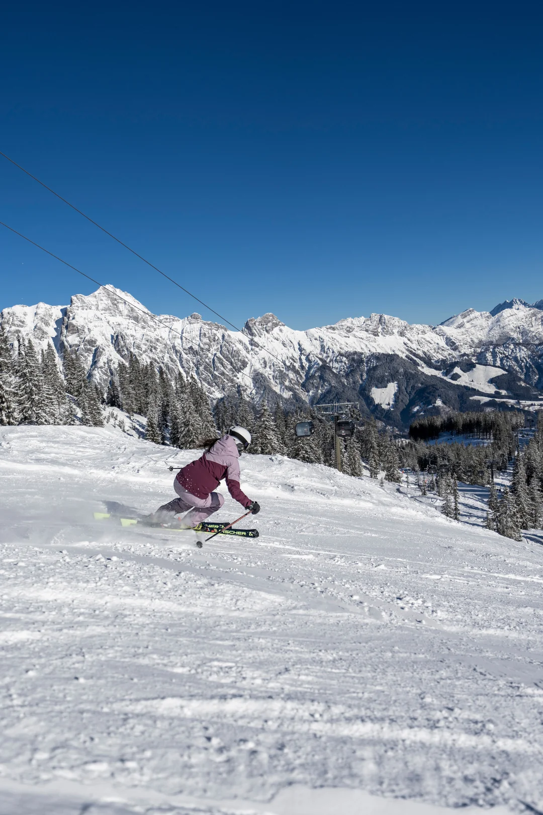 Skifahrerin auf Piste mit Steinberge-Panorama im Winter